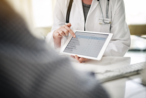 Assistant  showing patient online forms on a digital tablet
