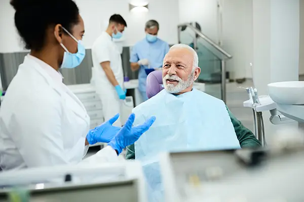 Older patient sitting in dental chair while dentist is explaining extraction procedure at Placentia Oral Surgery in Placentia, CA